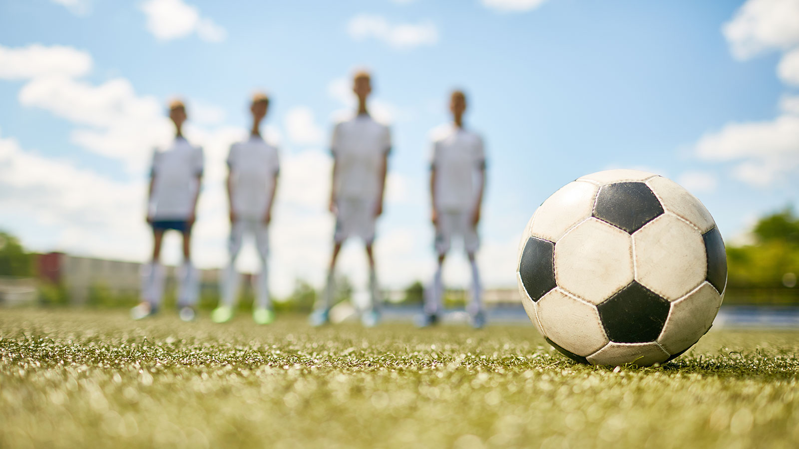 Fussball im Vordergrund, Fussballspieler im Hintergrund unscharf
